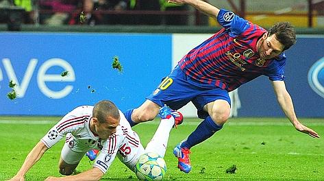 Pezzi di terreno in volo dopo un duello tra Messi e Mesbah in Milan-Barcellona. Afp