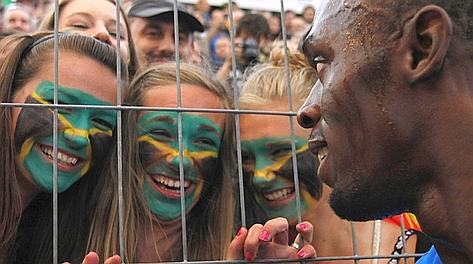 Tre tifose salutano l'idolo Bolt a fine gara. Reuters