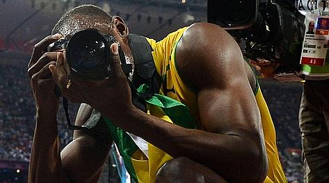 Usain Bolt scatta foto dopo l'oro olimpico nei 200. Afp