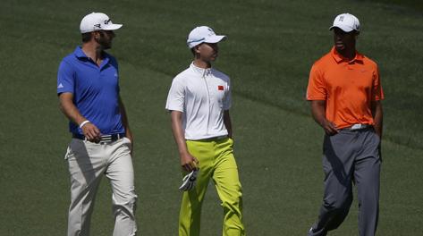 Il cinese Guan Tianlang (14 anni, al centro), passeggia sul green con Dustin Johnson e Tiger Woods. Reuters