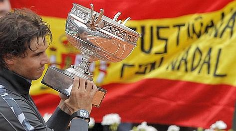 Rafa Nadal solleva il trofeo davanti alla bandiera spagnola. LaPresse