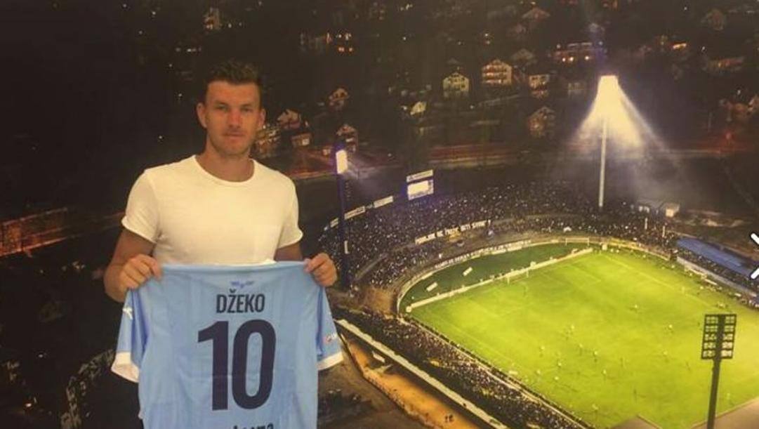 Edin Dzeko, 34 anni, posa davanti a una foto dello stadio Grbavica  