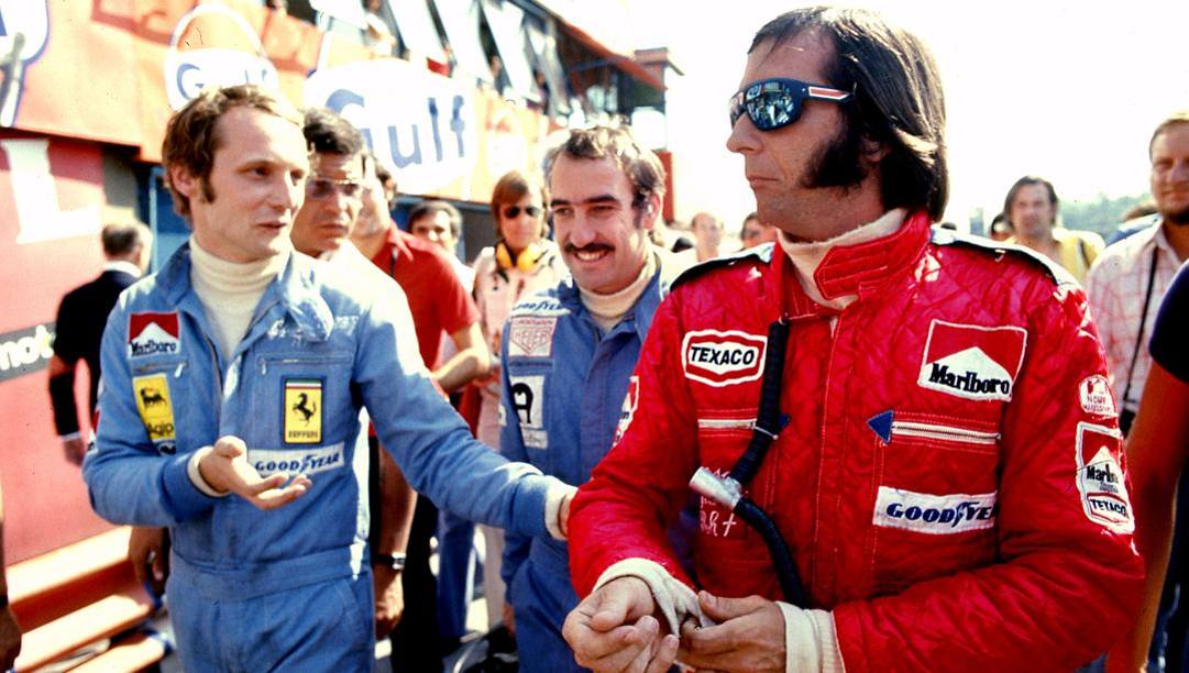 Fittipaldi, in rosso, parla con Lauda prima del GP; alle loro spalle Regazzoni. Lapresse 